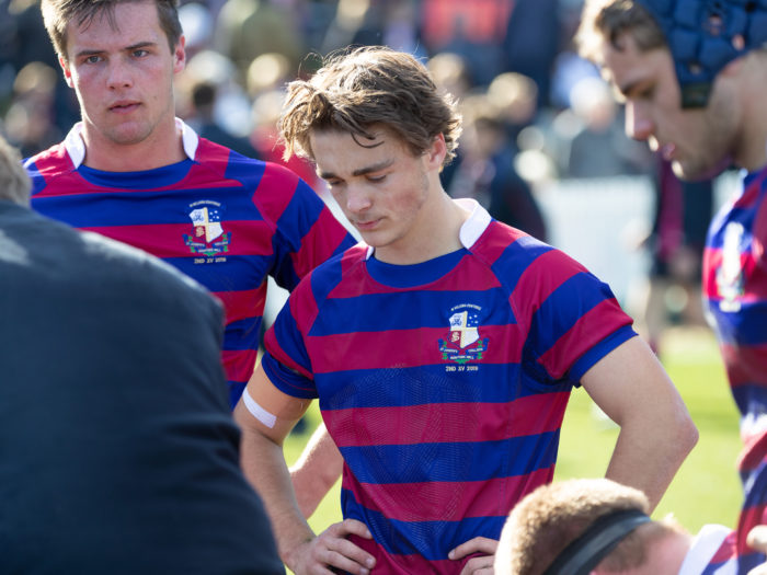 boys in rugby field in huddle with coach